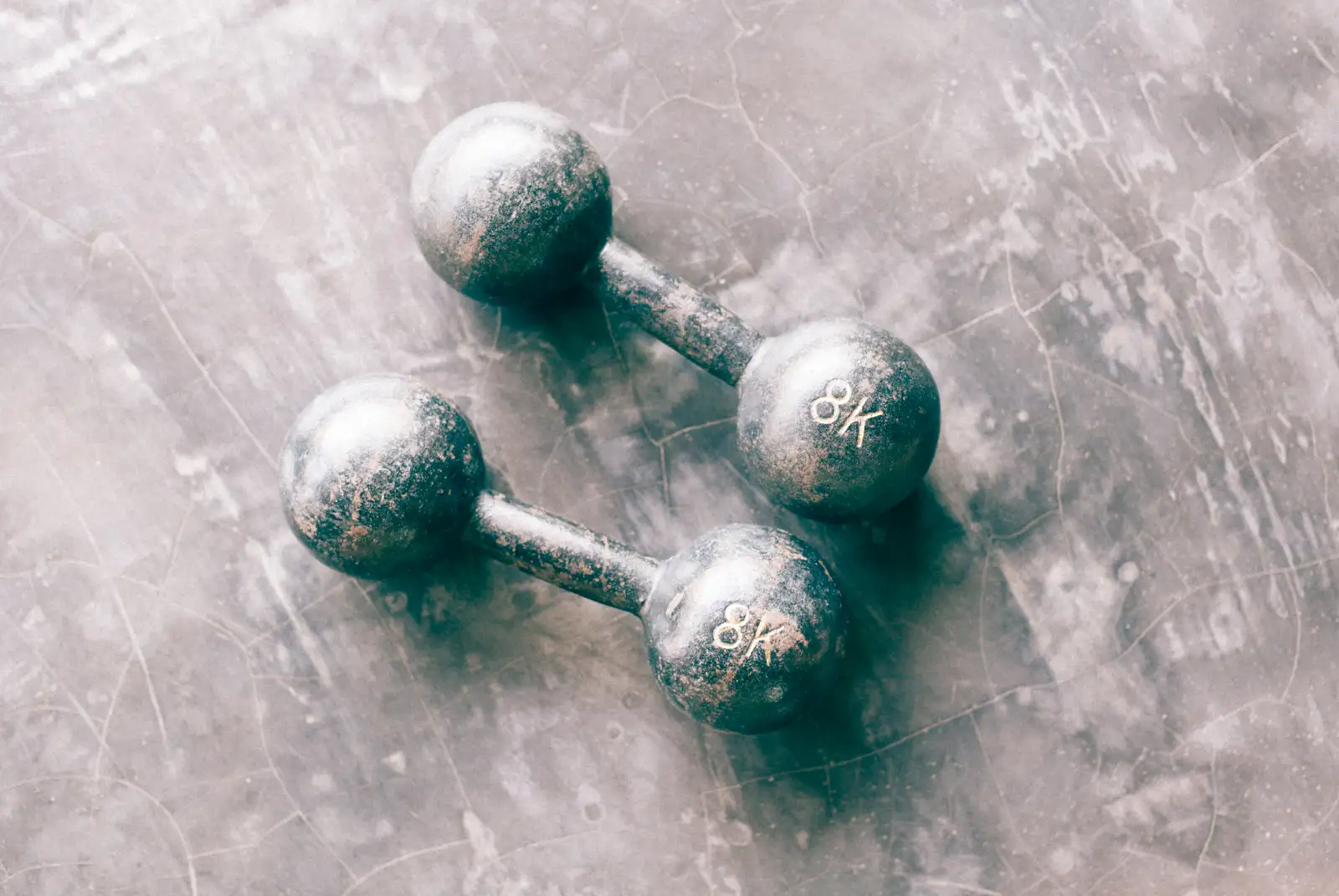 Two iron dumbbells on a gray stone floor